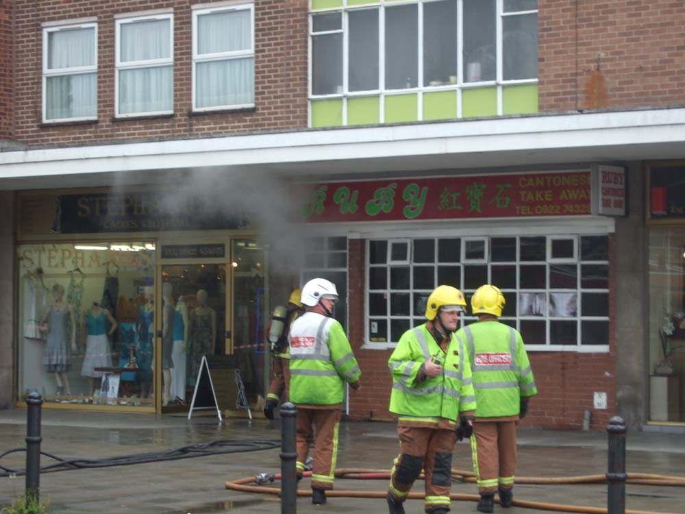 Fire crews with breathing apparatus enter burning building in Aldridge